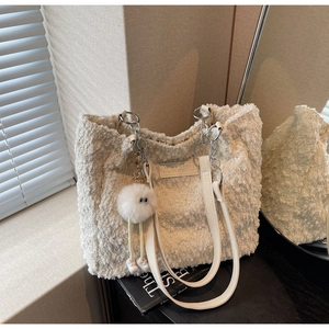 Detail of off-white plush tote bag featuring a monster charm and chain strap