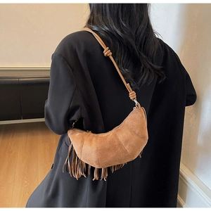 Detailed view of brown suede crescent bag with bohemian fringe and knotted shoulder strap