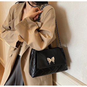 Détail du sac à bandoulière noir matelassé avec fermoir papillon argenté et chaîne