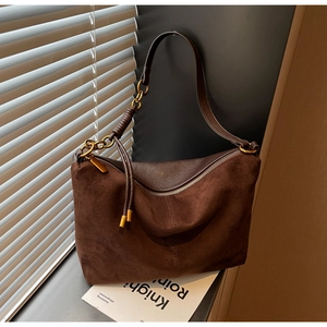 Close-up of vintage brown suede shoulder bag with woven leather handle and gold buckle