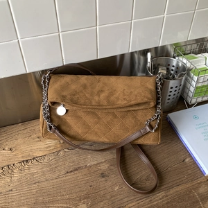Detailed macro view of brown suede shoulder bag featuring diamond quilted stitching