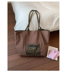 Detail of the large tote bag with leopard print handles and an 'OWN THE MOMENT' patch