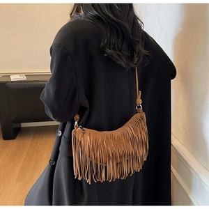 Detailed view of a brown suede crescent bag with bohemian fringe and shoulder strap