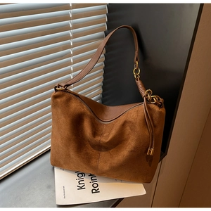 Close-up of brown suede bag texture with golden chain detail and fringe tassel decoration