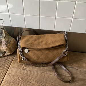 Detail of coffee suede shoulder bag with classic quilted diamond pattern and silver chain