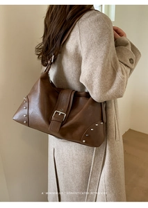 Close-up of retro brown PU leather shoulder bag with silver buckle and stud details
