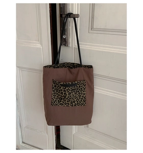 Detail view of large brown tote bag with leopard print pocket and inner lining accent