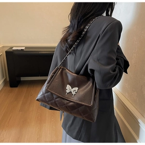 Gros plan d'un sac matelassé marron avec boucle papillon argentée et bandoulière