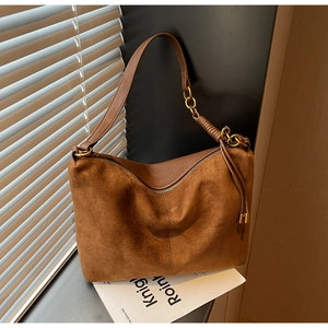 Detail of brown suede shoulder bag with gold ring hardware and leather zipper puller