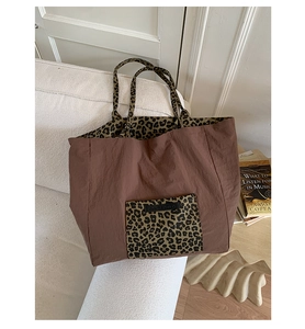 Detail of leopard print canvas tote bag with front pocket and branded label on sofa
