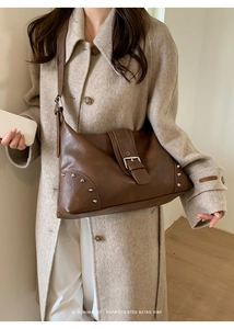 Close-up of a vintage brown leather tote bag with silver buckles and metallic rivets
