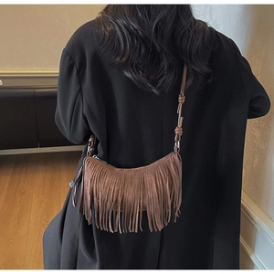 Detailed view of a brown suede moon bag with long fringes and knot shoulder strap detail