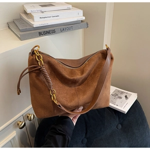 Detailed macro of dark brown suede hobo bag with gold metal chain and leather strap