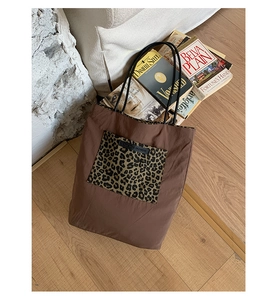 Close-up of brown nylon tote bag featuring leopard print pocket and black brand label