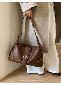 Close-up of brown retro leather tote bag featuring stylish side rivets and buckle strap