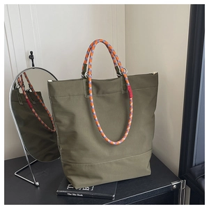 Detail of olive canvas tote bag with thick orange and blue braided rope handles