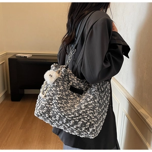 Detail of black and white bouclé tote bag with silver chain strap and plush charm