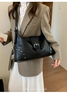 Detail of retro black leather shoulder bag featuring silver rivets and metal buckle
