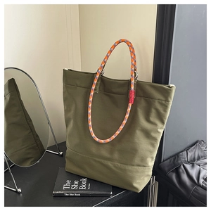 Detail of olive green tote bag featuring orange and blue braided rope handles