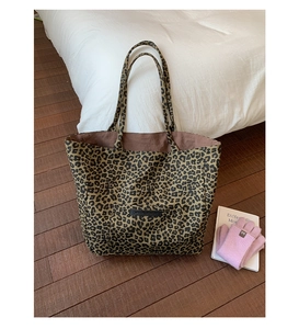 Close-up of leopard print tote bag featuring a leather tag and durable canvas texture
