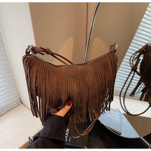 Detail of brown suede crescent bag featuring long bohemian tassels and zip closure
