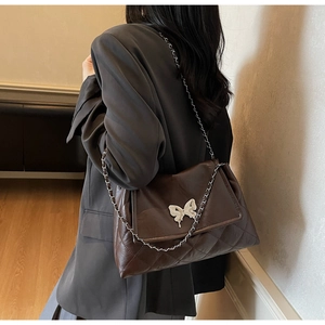 Vue détaillée du sac en cuir matelassé marron foncé avec un ornement papillon blanc chic