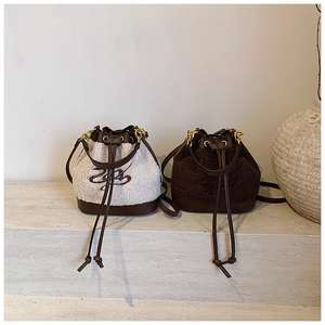 Detail of plush bucket bag in cream and brown with embroidery and chain strap