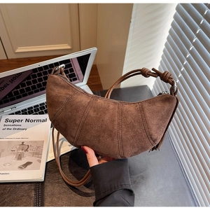 Detail of vintage brown suede crescent bag with radial stitching on an office desk