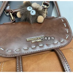 Dettaglio dello zaino vintage in pelle patchwork con cuciture e ciondolo in peluche