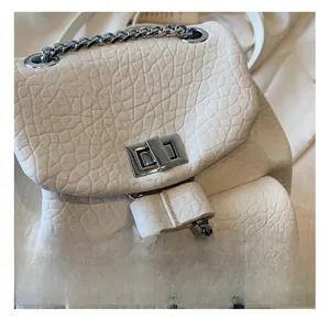 Close-up of the silver metal rotating lock and textured lychee leather on the bag
