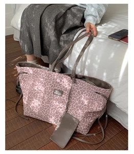Gros plan du sac cabas léopard rose avec logo en cuir et petite pochette assortie incluse