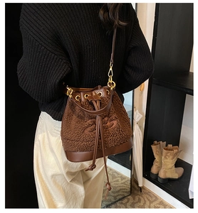 Close-up of brown plush bucket bag with leather base and drawstring closure on model