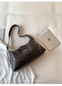 Close-up of retro dark brown leather tote bag featuring silver rivets and metal buckle detail