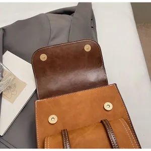 Dettaglio dello zaino in pelle vintage con fibbia magnetica dorata e cuciture bianche