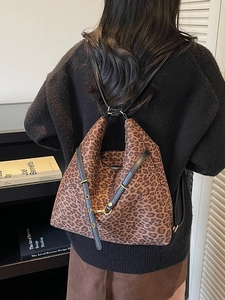 Fashionable leopard print bucket bag with leather strap shown as crossbody on model