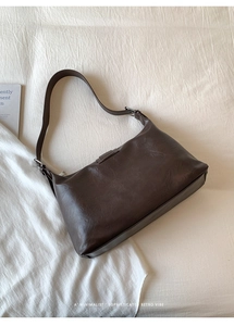 Close-up of a minimalist dark brown leather hobo bag with adjustable silver buckle