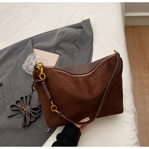 Detail of vintage brown suede shoulder bag with gold zipper and leather-wrapped metal ring