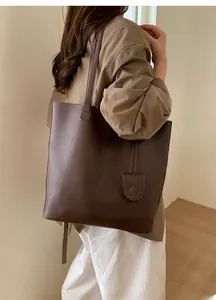 Detail of dark brown lychee leather bucket bag with shoulder strap and mini pouch charm