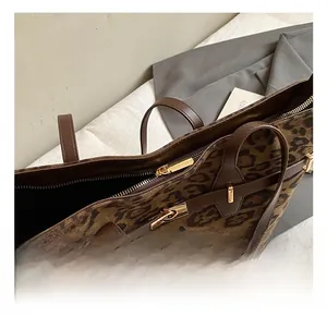Macro view of leopard print tote bag with brown leather strap and gold zipper detail
