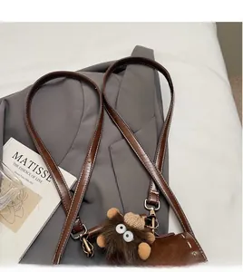 Dettaglio della tracolla dello zaino in similpelle marrone con charm a scimmia di peluche