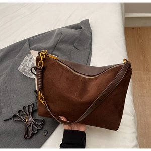 Detail of dark brown suede shoulder bag featuring a gold chain and smooth leather trim