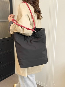 Minimalist black tote bag with red and gold braided rope handles for daily commuting