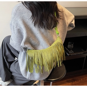 Detail of lime green suede crescent bag with long fringe and knotted strap detail