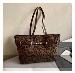 Detailed view of leopard print tote bag with brown handles and golden rotating metal buckle