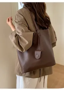 Deep brown litchi pattern leather bucket bag with slim strap shown on model in street style