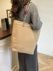 Minimalist large khaki tote bag with rope handles shown on a model in a cafe setting