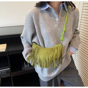 Close-up of avocado green crescent bag with long fringes and suede-like texture