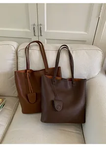 Detail view of large lychee texture leather tote bags in caramel brown and dark coffee colors