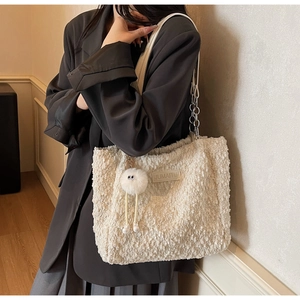 Detail of creamy white sherpa tote bag with metal chain strap and plush ball charm