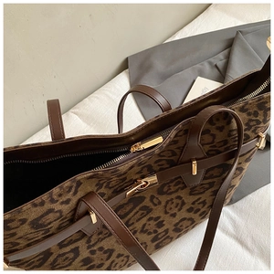 Detail of leopard print tote bag showing gold zipper and premium leather handles